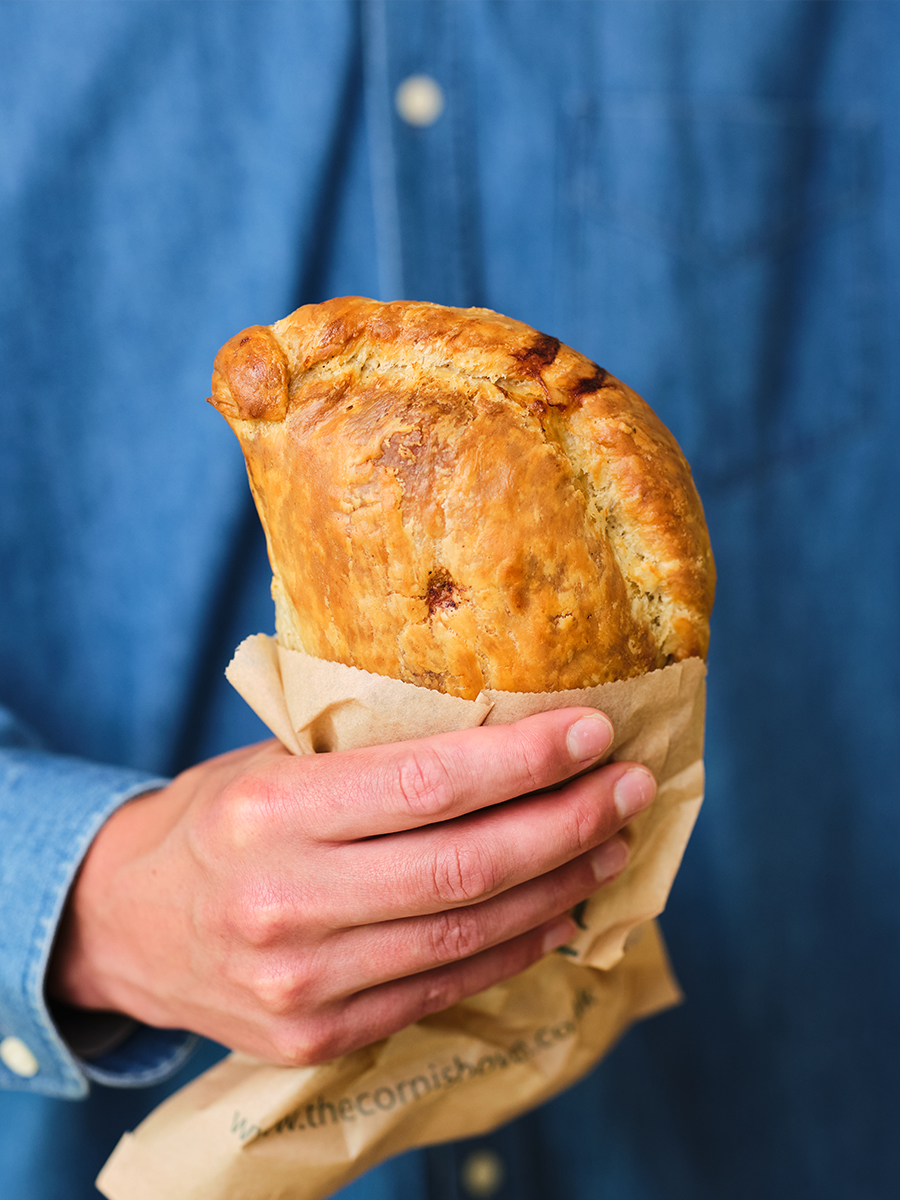 The Cornish Oven Flaky Pasty In Hand Blue Background